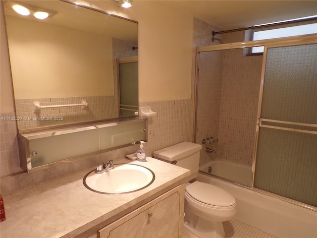 full bath with toilet, enclosed tub / shower combo, tile patterned flooring, vanity, and tile walls