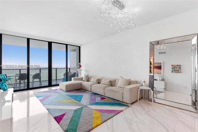 living room featuring visible vents, a water view, marble finish floor, a wall of windows, and a chandelier