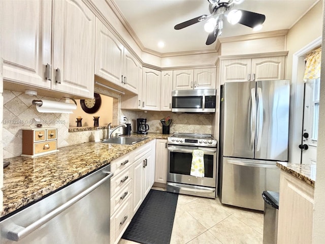 kitchen with appliances with stainless steel finishes, sink, decorative backsplash, ornamental molding, and light tile patterned floors