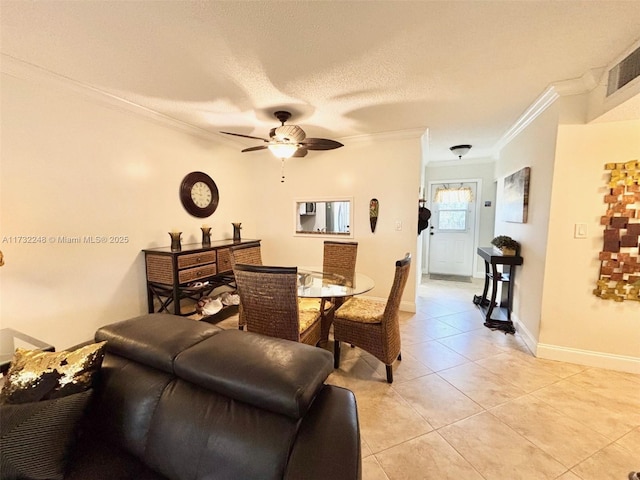 tiled dining space featuring ceiling fan, ornamental molding, and a textured ceiling