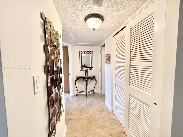 corridor featuring light tile patterned floors and a textured ceiling