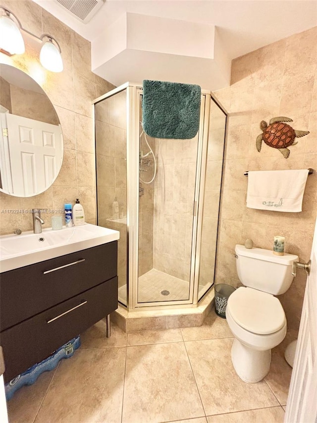 bathroom with toilet, tile walls, vanity, and a shower with shower door