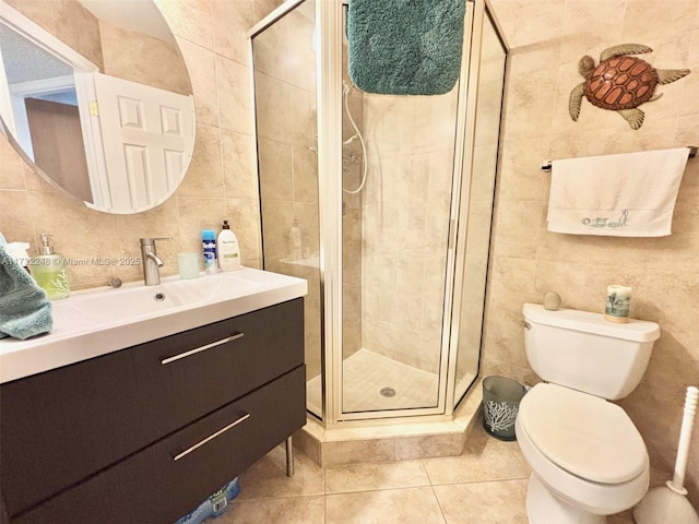 bathroom with vanity, toilet, a shower with door, and tile walls