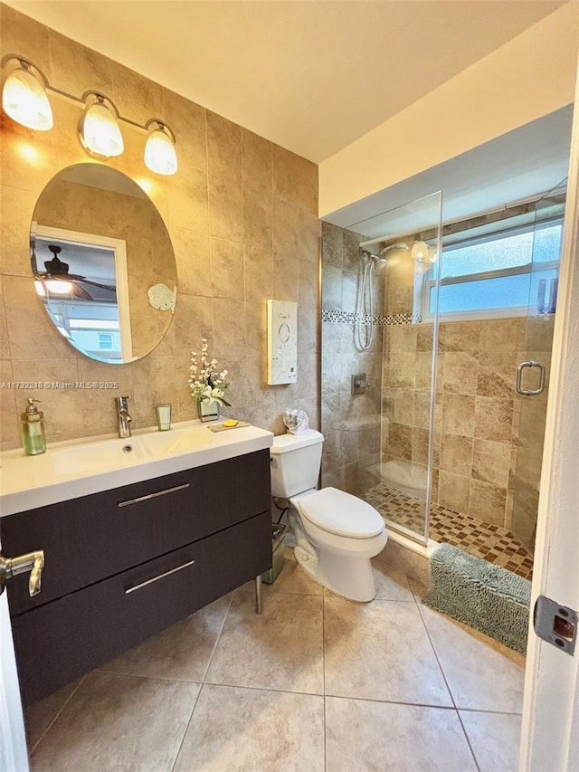 bathroom with tile walls, an enclosed shower, vanity, tile patterned floors, and toilet