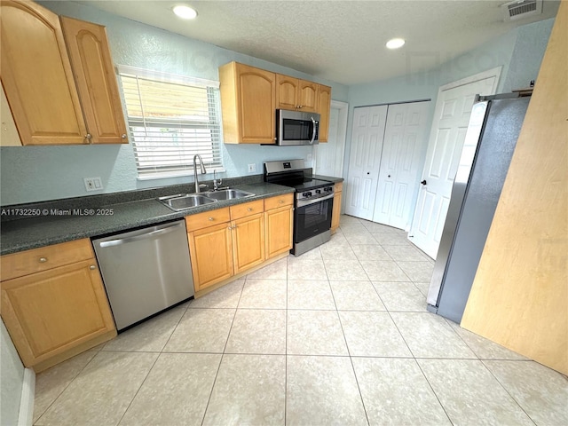 kitchen with stainless steel appliances, sink, a textured ceiling, and light tile patterned floors