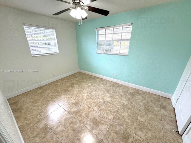 empty room featuring a wealth of natural light, ceiling fan, and light tile patterned floors