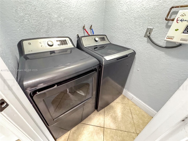 clothes washing area with light tile patterned floors and washer and clothes dryer