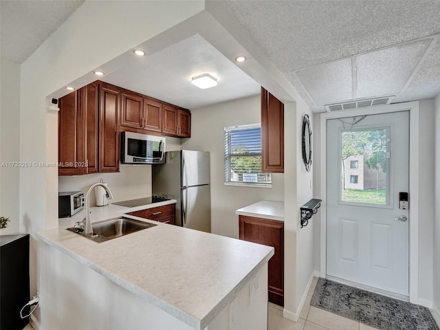 kitchen featuring sink, light tile patterned floors, appliances with stainless steel finishes, a healthy amount of sunlight, and kitchen peninsula