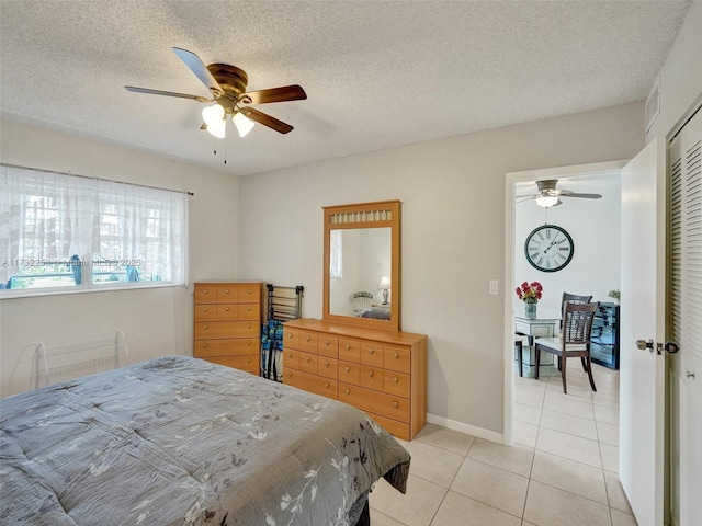 bedroom with light tile patterned floors, a textured ceiling, ceiling fan, and a closet