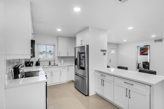 kitchen featuring sink, white cabinetry, light stone counters, stainless steel fridge with ice dispenser, and electric range