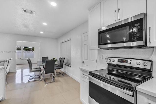 kitchen with white cabinetry, appliances with stainless steel finishes, and light tile patterned floors