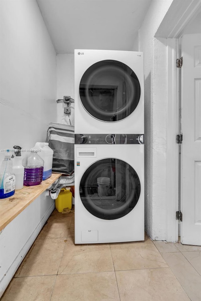 clothes washing area with stacked washing maching and dryer and light tile patterned floors