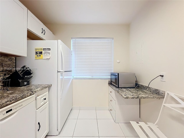 kitchen with white cabinetry, dark stone countertops, white appliances, and light tile patterned floors