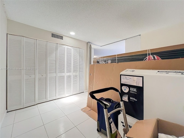 bedroom featuring a closet, a textured ceiling, and light tile patterned flooring