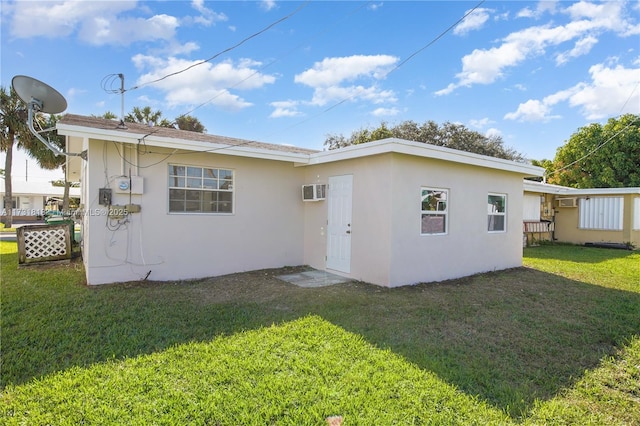 rear view of house with a yard and a wall mounted air conditioner