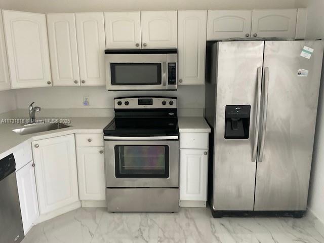 kitchen featuring stainless steel appliances, sink, and white cabinets