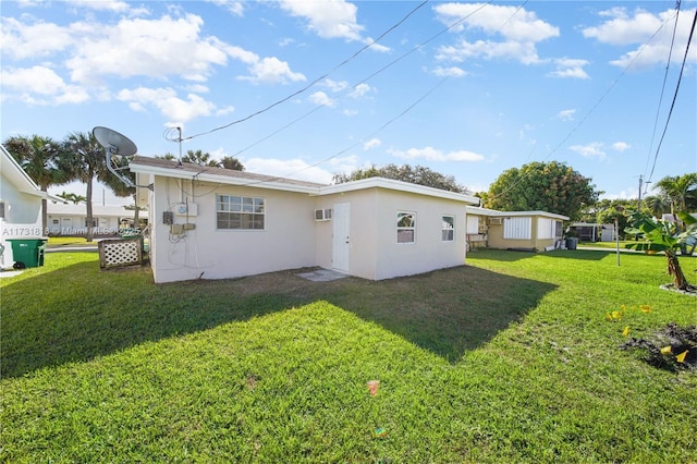 rear view of property featuring an AC wall unit and a yard