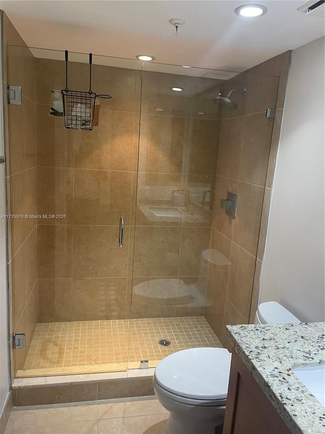 bathroom with tile patterned floors, toilet, a shower with door, and vanity