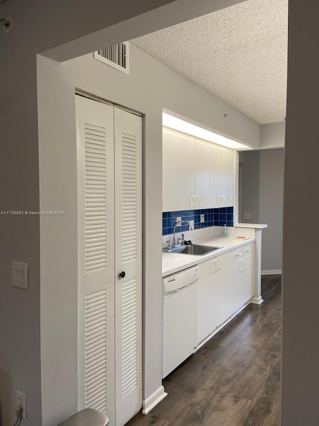 kitchen featuring sink, white dishwasher, tasteful backsplash, a textured ceiling, and white cabinets