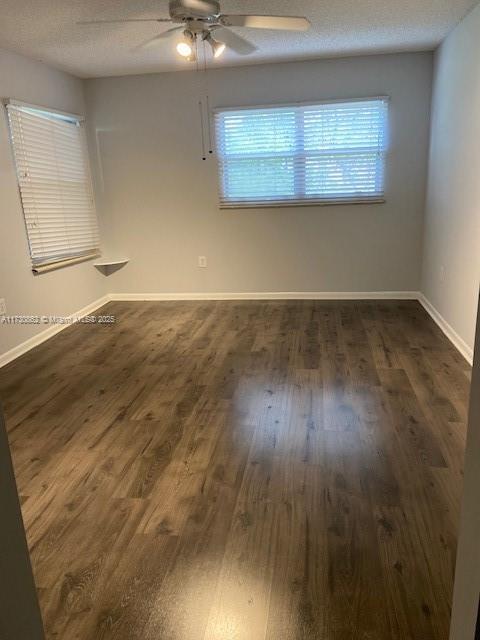 spare room featuring dark wood-type flooring, a textured ceiling, and ceiling fan