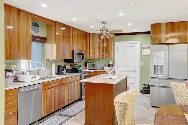 kitchen featuring sink, light stone counters, appliances with stainless steel finishes, a kitchen island, and ceiling fan