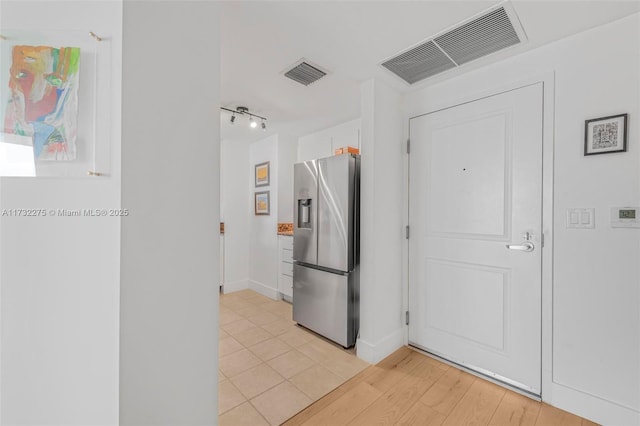 kitchen with white cabinetry, stainless steel fridge, and light tile patterned flooring