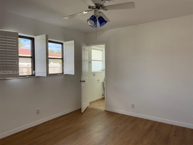 spare room with plenty of natural light, baseboards, and wood finished floors