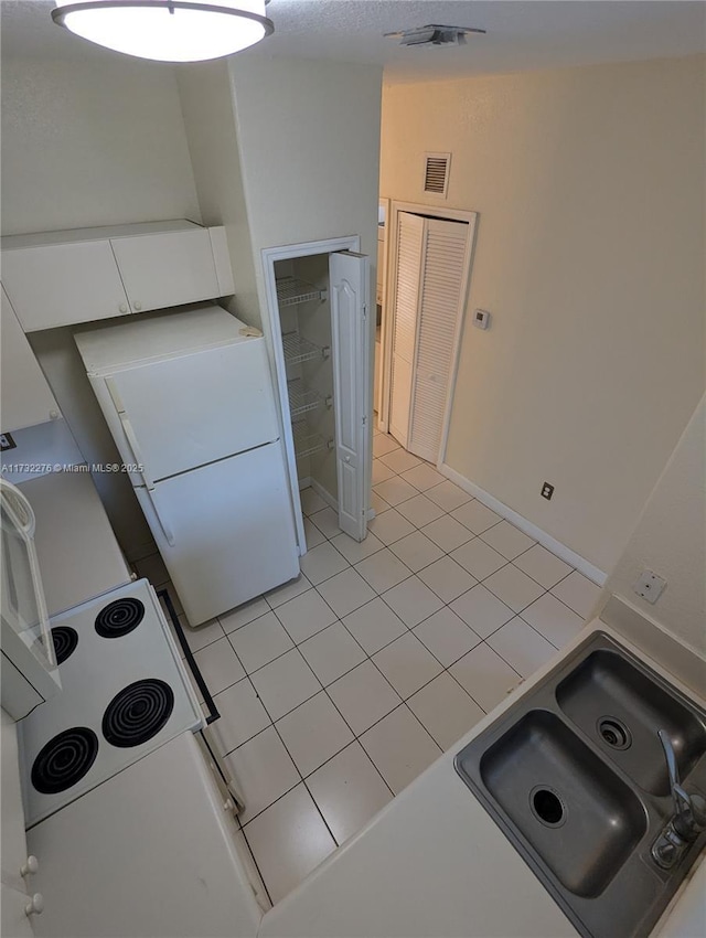 kitchen featuring white cabinetry, white fridge, sink, and light tile patterned floors