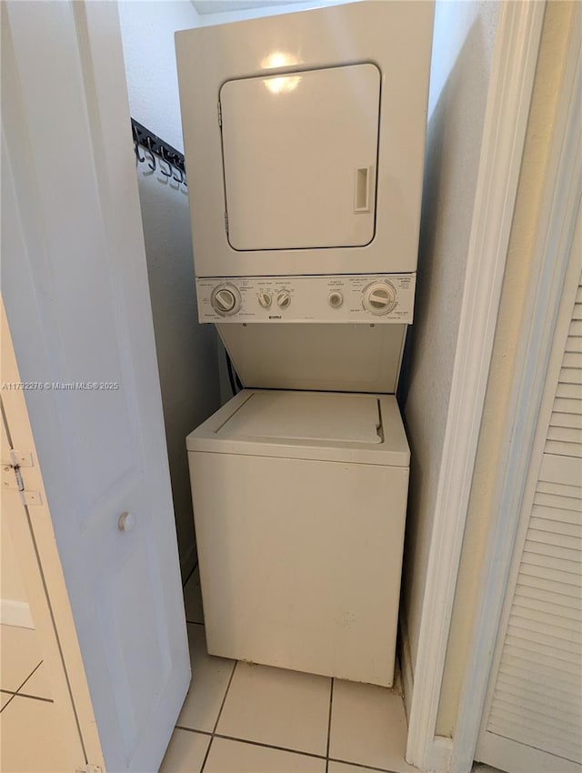 clothes washing area featuring stacked washing maching and dryer and light tile patterned floors