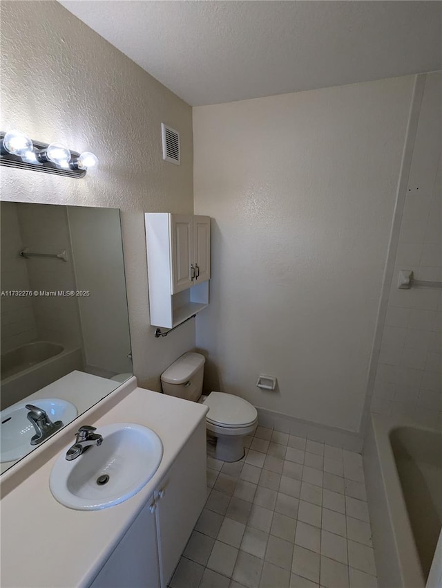 bathroom with a washtub, vanity, a textured ceiling, tile patterned floors, and toilet