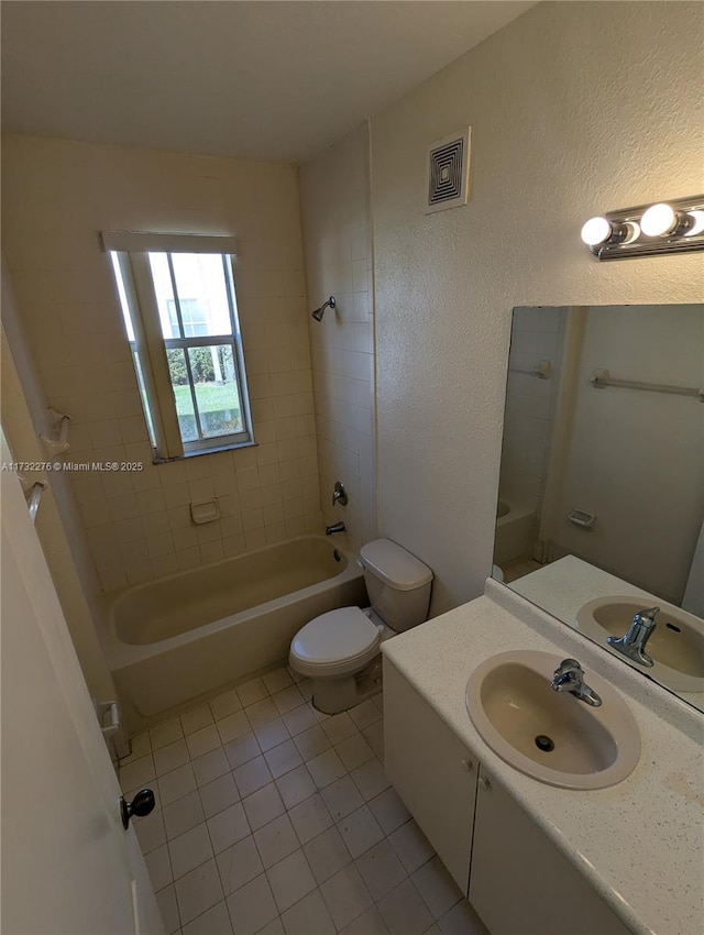 full bathroom with tiled shower / bath combo, vanity, tile patterned floors, and toilet