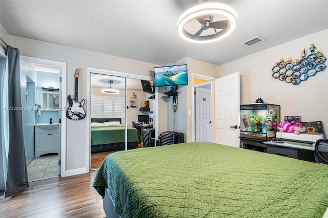 bedroom with sink, a closet, ensuite bathroom, and wood-type flooring