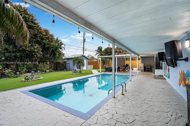 view of swimming pool with a shed, a patio, and a yard