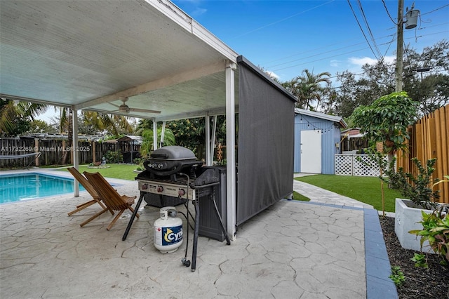 view of patio with a storage unit, ceiling fan, grilling area, and a fenced in pool