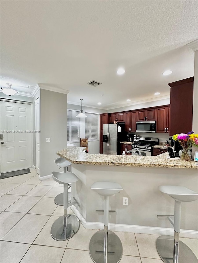 kitchen featuring light tile patterned floors, a breakfast bar, hanging light fixtures, stainless steel appliances, and kitchen peninsula