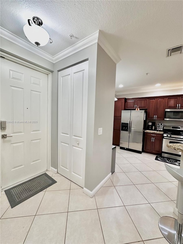 entryway featuring ornamental molding, a textured ceiling, and light tile patterned flooring