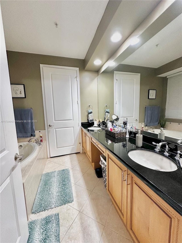 bathroom with tile patterned flooring, vanity, and tiled bath