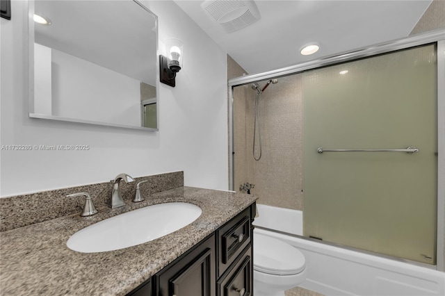 full bathroom with bath / shower combo with glass door, vanity, and toilet