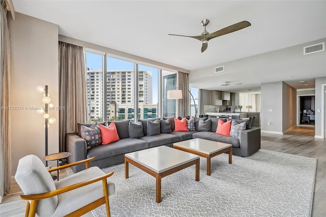 living room featuring ceiling fan, plenty of natural light, and light hardwood / wood-style floors