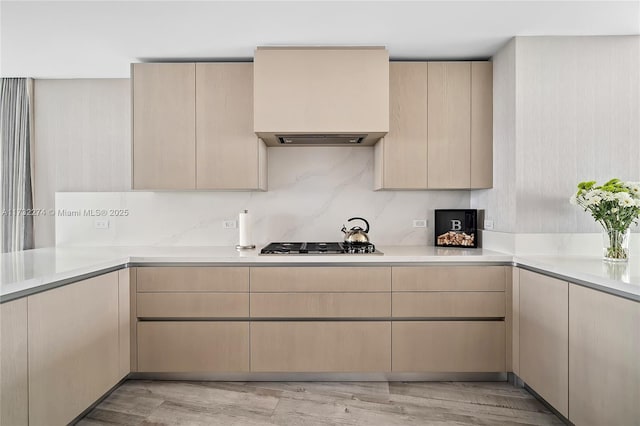 kitchen with tasteful backsplash, stainless steel gas cooktop, light brown cabinetry, and light wood-type flooring