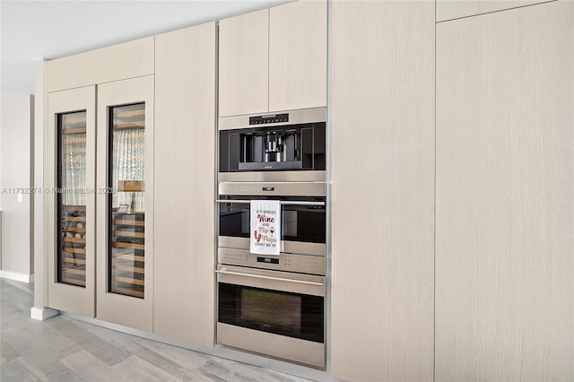 kitchen featuring double oven, light hardwood / wood-style floors, and cream cabinetry