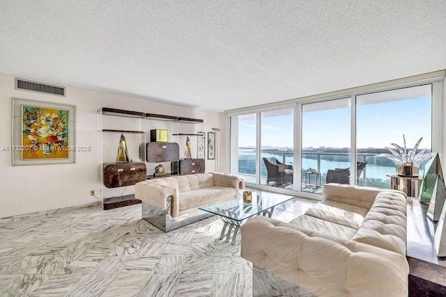 living room with expansive windows, a textured ceiling, and a water view