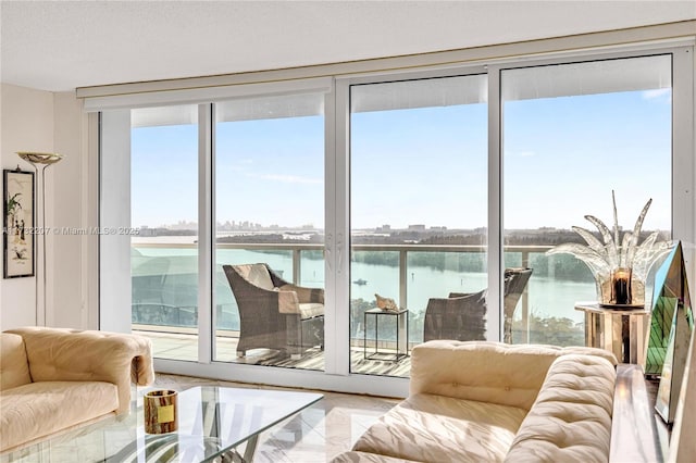 entryway with expansive windows, a water view, a healthy amount of sunlight, and a textured ceiling