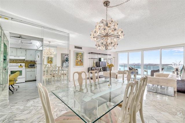 dining space with a water view, an inviting chandelier, and a textured ceiling