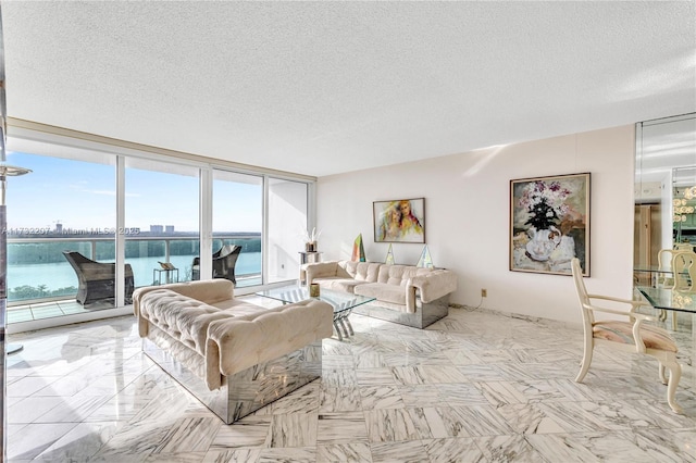 living room with expansive windows, a water view, and a textured ceiling