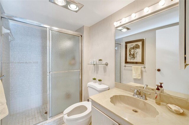 bathroom with vanity, toilet, and a shower with door