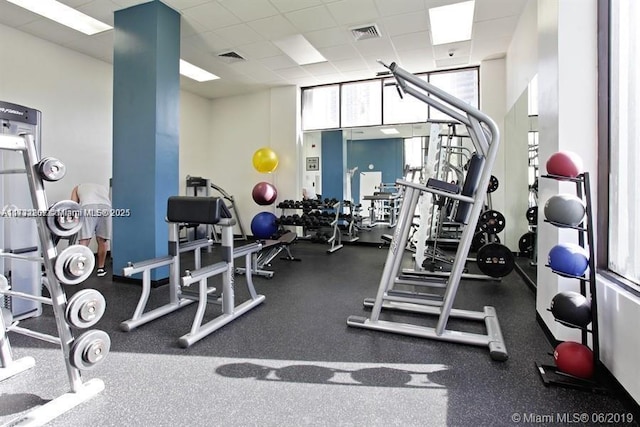 workout area with a drop ceiling and a wall of windows