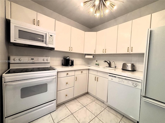 kitchen featuring light tile patterned floors, white appliances, a chandelier, and white cabinets