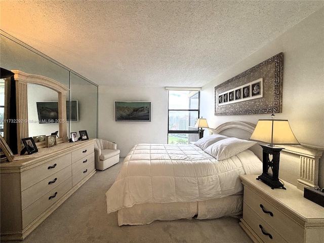 bedroom featuring floor to ceiling windows, light carpet, and a textured ceiling