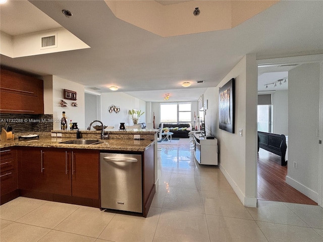 kitchen featuring light stone counters, sink, decorative backsplash, and kitchen peninsula